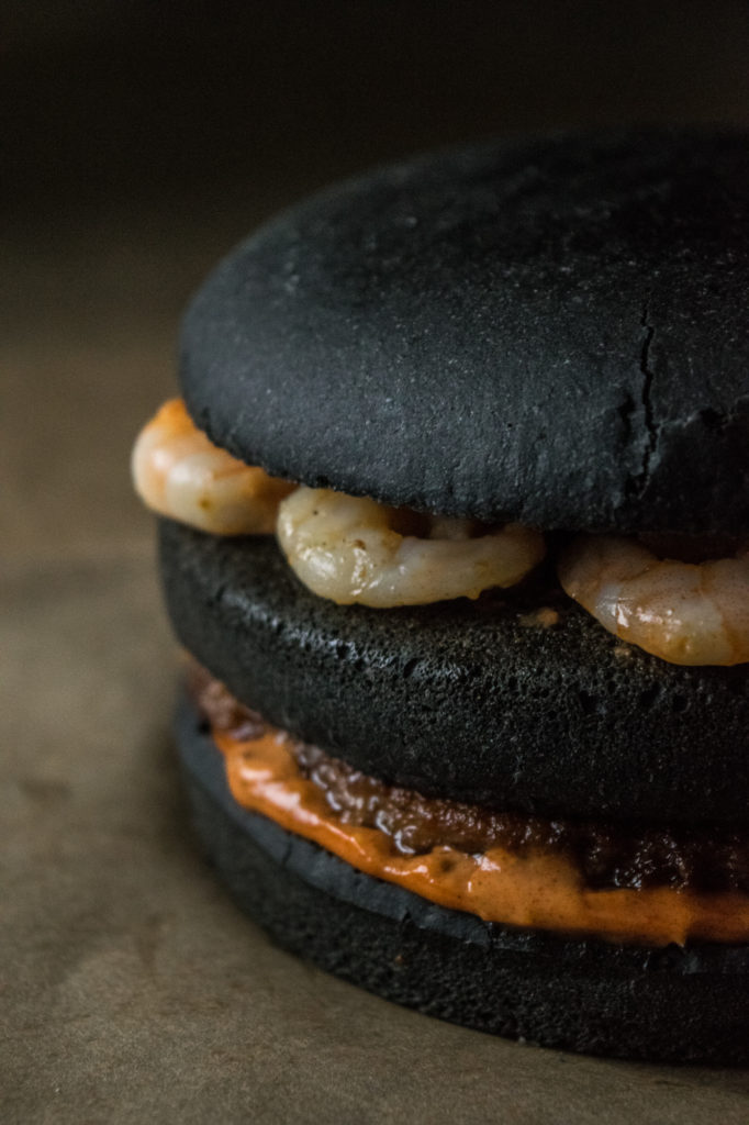 black burger with chorizo patty, manchego cheese and shrimps